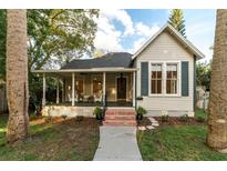 Charming home with a inviting front porch, dark shutters, and lush tropical landscaping at 911 S Oak Ave, Sanford, FL 32771