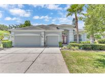 Beautiful single-story home with a well-manicured lawn, three-car garage, and a charming red front door at 10417 Oakview Pointe Ter, Gotha, FL 34734
