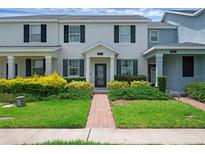Inviting townhome featuring a well-manicured lawn and a charming brick pathway leading to the front door at 11812 Metaphor Aly, Orlando, FL 32832