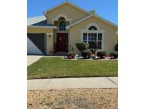 Charming home featuring a red door, manicured lawn, and decorative landscaping, creating inviting curb appeal at 1199 Stoneham Dr, Groveland, FL 34736