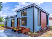 Charming exterior of blue home with updated planter, and a wooden door with wreath, under blue sky at 221 E Fern Dr, Orange City, FL 32763