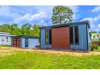 Exterior showing the side of the blue home with a brown accent section, and a detached shed at 221 E Fern Dr, Orange City, FL 32763