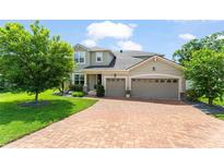 Charming two-story home with a brick driveway, a manicured lawn, and a three-car garage at 2401 Oxmoor Dr, Deland, FL 32724