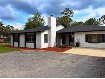 Charming single-story home featuring a white exterior, black trim, and well-manicured landscaping at 2630 S Tanner Rd, Orlando, FL 32820