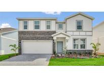 Two-story home with stone accents, a well-maintained lawn, and a paved driveway leading to a two-car garage at 3082 Mahalo Dr, Davenport, FL 33897