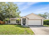 Charming single-story home featuring an attached two car garage and mature trees in the front yard at 3304 Vancouver Ave, Deltona, FL 32738