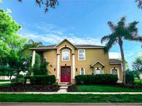 Charming two-story home with a well-manicured lawn, mature trees, and a red front door at 357 Fairway Pointe Cir, Orlando, FL 32828