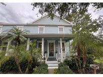 Charming two-story home with a light blue exterior, welcoming front porch, and lush tropical landscaping at 3963 Turow Ln, Orlando, FL 32828