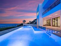 Stunning infinity pool overlooking the ocean at sunset with a modern, luxurious house at 4647 Van Kleeck Dr, New Smyrna Beach, FL 32169