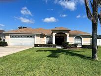 Charming single-story home with a well-manicured lawn, lush landscaping, and an attached two-car garage at 517 Westwind Dr, Davenport, FL 33896