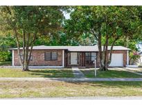 Charming brick home featuring mature trees, a manicured lawn, and an inviting front entrance at 657 Lear Ter, Deltona, FL 32725