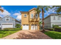 Inviting two-story home with a brick driveway, lush landscaping and attached two-car garage at 7411 Excitement Dr, Reunion, FL 34747