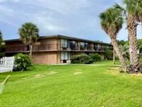Low-rise condo with brick facade, complemented by a well-manicured green lawn and mature trees at 7900 S Orange Blossom Trl # 1099, Orlando, FL 32809