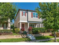 Charming two-story home with a red door, gray exterior paint and well-manicured landscaping at 9348 Meadow Hunt Way, Winter Garden, FL 34787
