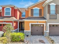 Inviting exterior showcasing a well-maintained multi-colored townhome with an attached garage and mature landscaping at 9559 Silver Buttonwood St, Orlando, FL 32832