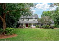 Charming two-story home with manicured lawn, mature trees, and a welcoming front porch at 104 Forest Point Ln, Longwood, FL 32779
