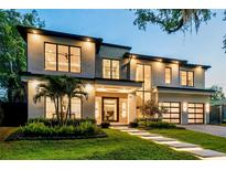 Stunning modern home with lush landscaping, illuminated walkway, and sleek, black-trimmed windows at 1211 Munster St, Orlando, FL 32803
