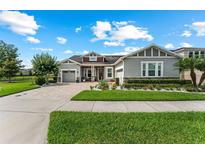Charming gray single-story home with a well-manicured lawn and a brick driveway at 14880 Ellingsworth Ln, Winter Garden, FL 34787