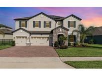 Stunning two-story home showcasing a three-car garage, stone accents, and a well-manicured lawn at 2060 Panoramic Cir, Apopka, FL 32703