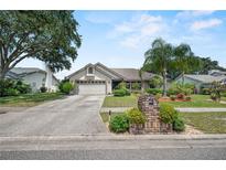 Charming single-story home with a well-manicured lawn, mature trees, and a two-car garage on a sunny day at 2209 Fairglenn Way, Winter Park, FL 32792