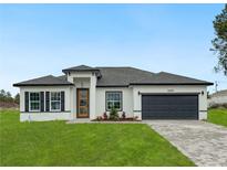 Charming single-story home boasts a well-manicured lawn, striking black and white design, and paved driveway at 3420 Sw 130Th Lane Rd, Ocala, FL 34473