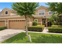 Inviting tan two-story home featuring a two-car garage and manicured landscaping at 479 Harbor Winds Ct, Winter Springs, FL 32708