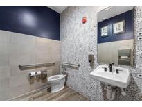 Modern bathroom with patterned tile accent wall, grab bars, and sleek fixtures at 6615 Leo Ln, St Cloud, FL 34773
