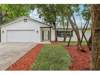 Charming single-story home with a freshly painted white brick exterior, landscaped front yard, and attached garage at 7124 Turquoise Ln, Orlando, FL 32807