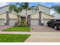 Modern townhomes feature stone accents, attached garages, and well-manicured lawns at 877 Ocean Course Ave, Davenport, FL 33896