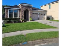 Charming single-story home with stone accents, manicured lawn, and a paved driveway leading to a two-car garage at 13842 Pickett Reserve Ct, Orlando, FL 32826