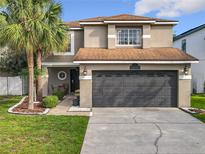 Inviting home featuring a well-manicured lawn, mature palm trees, and a two-car garage at 1803 Meadow Pond Way, Orlando, FL 32824