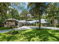 Charming brick home featuring a metal roof, mature trees, a circular driveway and lush landscaping at 20 Twelve Oaks Trl, Ormond Beach, FL 32174
