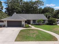 Charming single-story home featuring a well-manicured lawn, mature trees, and an attached two-car garage at 2122 Palm Crest Dr, Apopka, FL 32712
