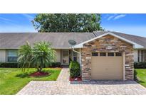 Charming villa featuring brick accents, a paved driveway, and a well-manicured lawn with a young palm tree at 2724 Shelby Ruth Pl, St Cloud, FL 34769