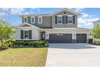 Charming two-story home with a three-car garage, manicured lawn and neutral-toned exterior at 31792 Broadwater Ave, Leesburg, FL 34748