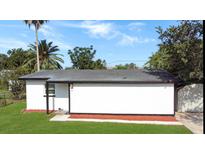 Side view of a white home with a dark roof and a well-maintained lawn at 49 Orange Park Blvd, Lake Wales, FL 33898