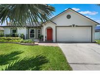 Charming single-story home with an attached two-car garage, a well-manicured lawn, and an inviting red front door at 719 Stevelynn Cir, Winter Garden, FL 34787