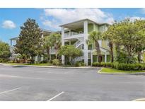 A beautiful exterior view of a green and white apartment building with palm trees and parking at 110 Watling Way # 25204, Davenport, FL 33837
