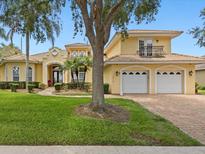 Inviting two-story yellow home featuring a tile roof, manicured lawn, and a two-car garage at 1319 Johns Cove Ln, Oakland, FL 34787