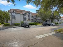 Two-story condo building with gray facade, balconies, and ample parking at 13917 Fairway Island Dr # 931, Orlando, FL 32837