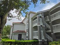 Low-angle view of a multi-story building with a red tiled roof and gray and white color scheme at 13917 Fairway Island Dr # 931, Orlando, FL 32837