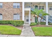 Well-maintained building entrance with brick accents, green shrubs, and walkway to first floor unit at 141 Reserve Cir # 113, Oviedo, FL 32765