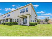 Well-maintained backyard featuring a covered patio with rocking chairs and lush green landscaping at 15241 Sunrise Grove Ct, Winter Garden, FL 34787