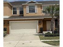 Inviting townhouse featuring a two-car garage and lush landscaping at 3308 Rodrick Cir, Orlando, FL 32824