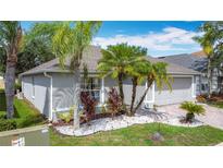 Well-maintained home with a brick driveway, manicured lawn, and tropical landscaping featuring palm trees at 4611 Cumbrian Lakes Dr, Kissimmee, FL 34746
