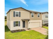Charming two-story home with neutral siding, gray shutters, brick driveway and a well-manicured lawn at 491 Whistling Duck Trl, St Cloud, FL 34771