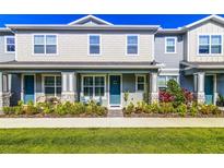 Charming two-story townhome featuring a quaint front porch, blue door, and landscaped front yard at 625 Dogfish Ln, Debary, FL 32713