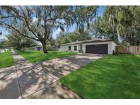 Charming single-story home boasts lush lawn, mature trees, and a long driveway leading to an attached two-car garage at 898 Shed St, Oviedo, FL 32765
