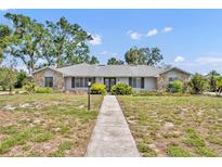 Charming single-story home with stone accents, mature trees, and walkway leading to the front entrance at 1115 Lake Francis Dr, Apopka, FL 32712