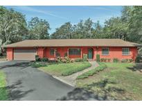 Charming single-story home featuring a lush front yard, covered porch with seating, and an attached garage at 127 Oak Ln, Ormond Beach, FL 32174